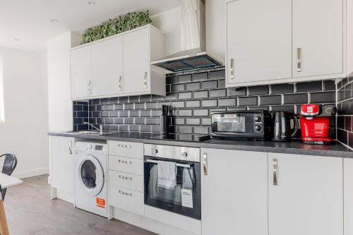 泰晤士河畔金斯顿Boutique Vertigo Apartment Central Kingston/London的厨房配有白色橱柜、洗衣机和烘干机