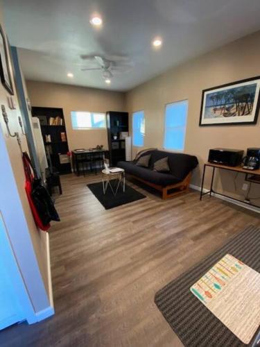 圣地亚哥The studio apartment in Clairemont - New AC unit的客厅设有黑色沙发和木地板