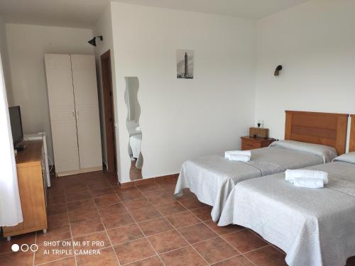 加的斯Vistas al faro的一间带两张床的卧室,铺有瓷砖地板。