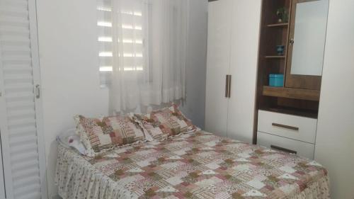 瓜鲁雅Familia Rodrigues的一间卧室配有一张带被子的床和一扇窗户