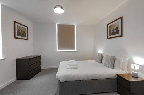 海伍德Comfy 1BR Apartment with Great Amenities的一间白色卧室,配有床和床头柜