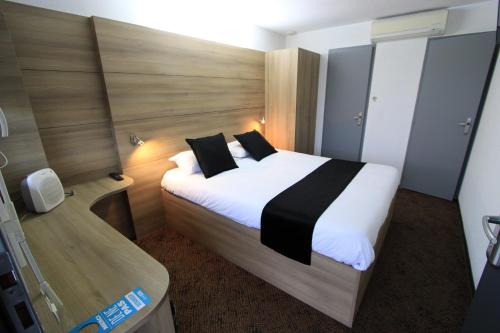 卢代阿克Enzo Hotels Loudeac By Kyriad Direct的卧室配有一张带黑色枕头的大型白色床。