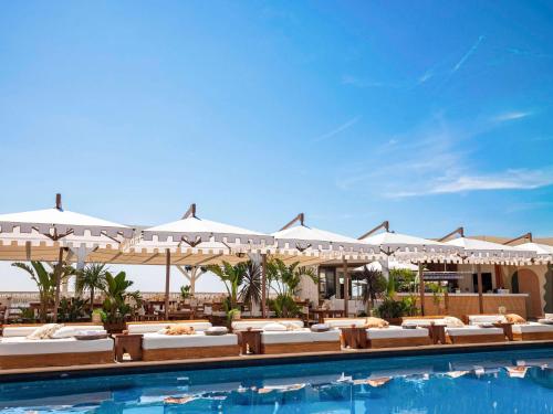 蒙特卡罗费尔蒙酒店&度假村的度假村的游泳池配有桌子和遮阳伞