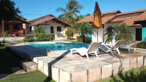 卡诺格布拉达奥托和卡林纳度假屋的房屋前的带椅子和遮阳伞的游泳池