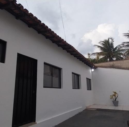 乌贝拉巴Casa próxima ao centro!的一间白色的房子,有黑色的门和棕榈树