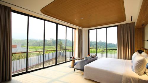 库宁岸Hotel Santika Premiere Linggarjati - Kuningan的一间卧室设有一张大床和大窗户