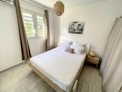 法兰西堡La Villa Rosa的一间卧室配有一张带白色床单的床和一扇窗户。