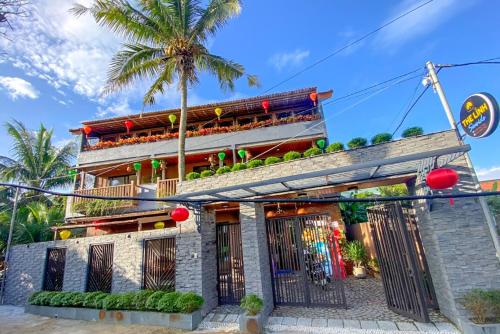 会安The Linh Seaside Villa Hoi An的前面有棕榈树的建筑