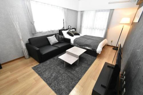 Susakiuramachicoco de minpaku 今泉的客厅配有床和黑色沙发