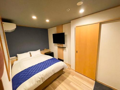 福冈NK Hotels的一间卧室配有一张床和一台平面电视