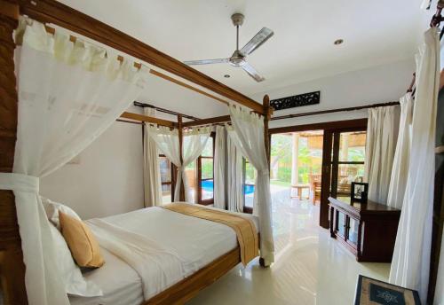 沙努尔巴厘岛翡翠别墅酒店的一间卧室配有带窗帘的天蓬床