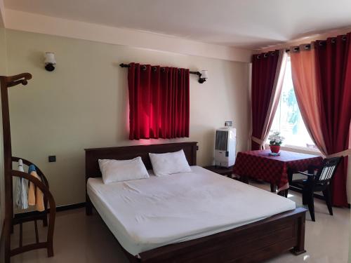 马拉维拉Eventide Beach Resort的一间卧室配有一张带红色窗帘的床和一张桌子