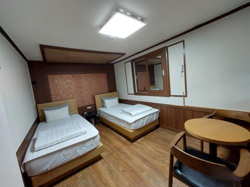 釜山Prince Motel的客房设有两张床、一张桌子和镜子