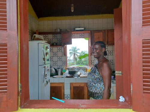 PrincipeCasa Mãe - Inn的站在带冰箱的厨房中的女人
