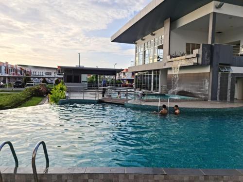 帕帕尔RHR Deluxe GuestHouse Kinarut Papar Sabah - Mountain View的两人在大楼前的游泳池里