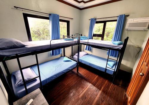 TanauanLeynes Taal Lake Resort and Hostel的客房设有三张双层床和一扇窗户。