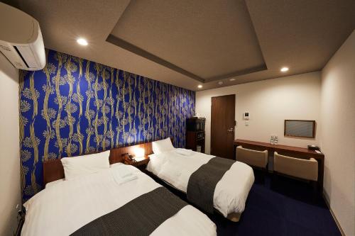 GiommachiHOTEL SUHAANA的酒店客房设有两张床和蓝色的墙壁。