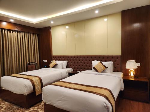 斯里曼加尔乌帕齐拉Paragon Hotel and Resort的酒店客房,设有两张床和一盏灯