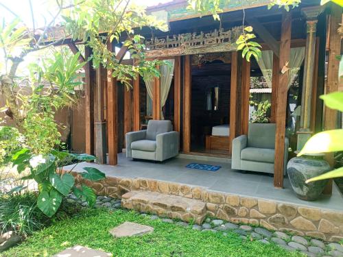 登巴萨Katang - Katang Guest House的一个带两把椅子的庭院和一座房子