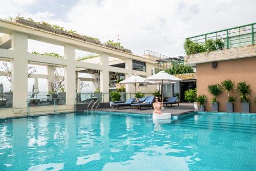 岘港Canvas Danang Beach Hotel的一位女士站在酒店的游泳池里
