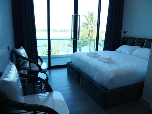 Pool Villa Rimkhong Nakhorn Panom的一间卧室配有床和椅子以及大窗户