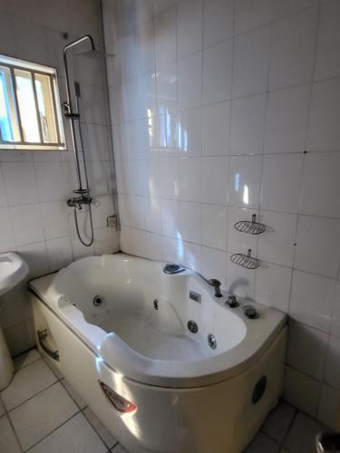 拉各斯Entire 3 Bedroom Bungalow - Home away from home的白色瓷砖浴室内的浴缸