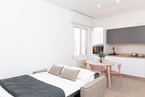 梅莱尼亚诺New Exclusive Melegnano Apartments- Near train station的一间卧室配有一张床铺和一张桌子,还设有一间厨房