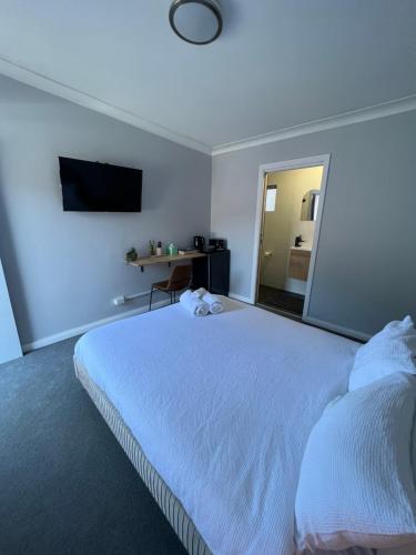 AdelongGold Reef Adelong的卧室配有白色的床和镜子