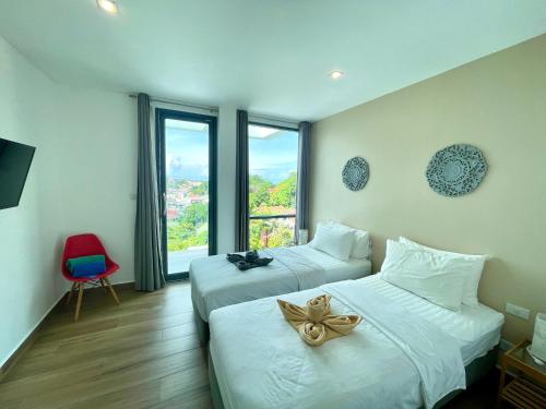 卡塔海滩Baan Saint-Tropez Seaview Villas Kata Beach的酒店客房设有两张床和窗户。