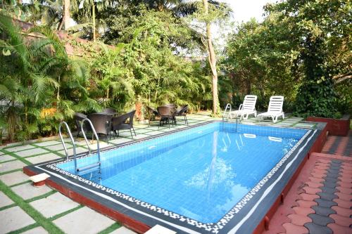 Moira4BHK Private Pool villa in North Goa and Kayaking nearby!!的一个带椅子和桌子的游泳池