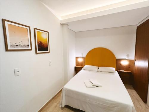 南圣弗朗西斯科Babitonga Hostel - 100m da Prainha的卧室配有白色的床和木制床头板