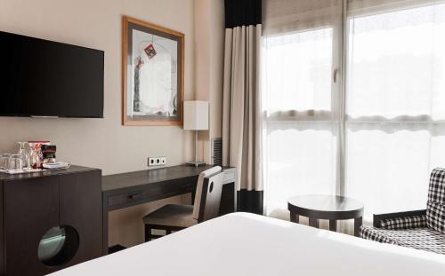 瓦伦西亚NH瓦伦西亚中心酒店的配有一张床和一张书桌的酒店客房