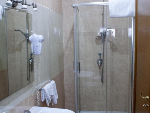 那不勒斯Hotel Serena的带淋浴的浴室,浴室设有玻璃淋浴间,位于后门