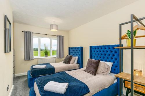 LincolnshireKime Contractor & Holiday Home的一间卧室设有两张床和蓝色床头板