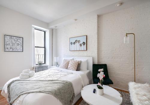 纽约Beautiful Studio Apartment At East Side的一间白色卧室,配有一张大床和两张桌子