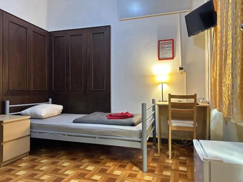 布达佩斯Kecskeméti Rooms的一间卧室配有一张床、一张书桌和一台电视