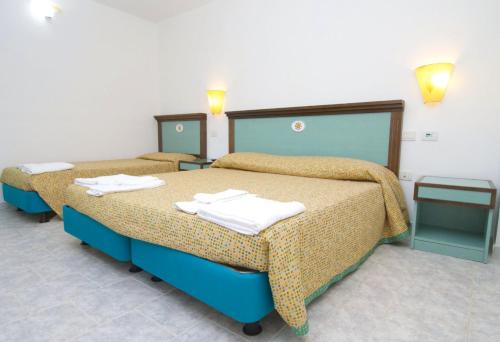 Casa dello StumioVillaggio Club Baia Dei Gigli的两张位于酒店客房的床,配有毛巾