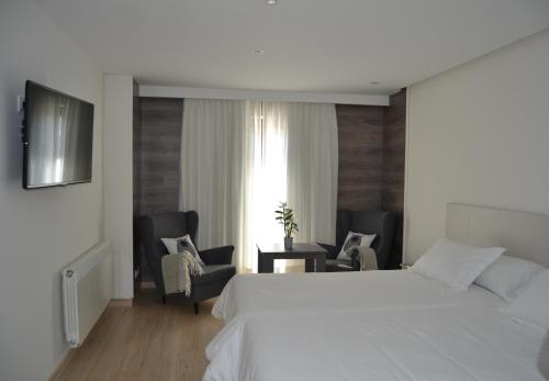 普韦布拉桑纳比亚维多利亚酒店的卧室配有一张白色大床和椅子