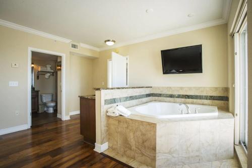圣徒皮特海滩Crystal Palms Beach Resort的带浴缸的大浴室和墙上的电视