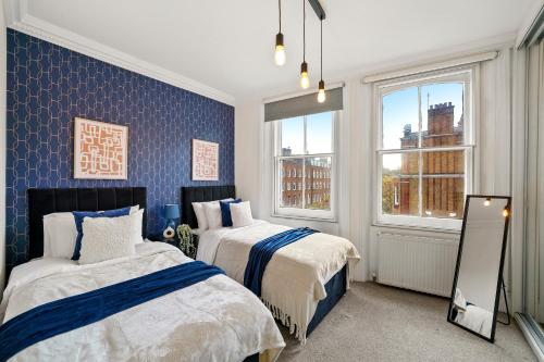 伦敦Delightful Flat in London - Sleeps 6的一间卧室设有两张床和两个窗户。