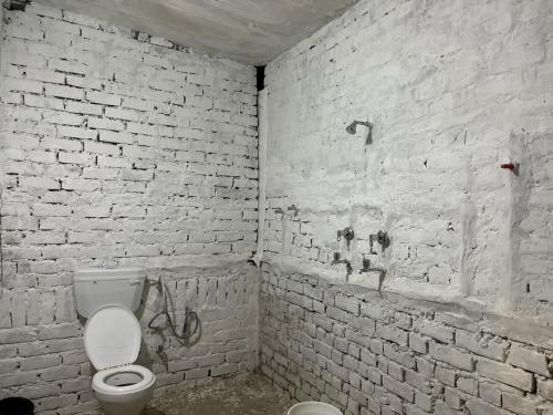 布什格尔Baba hostel的一间带卫生间和白色砖墙的浴室
