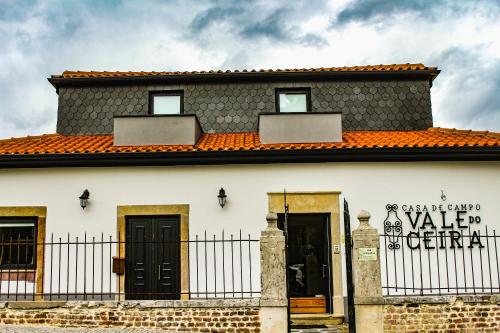 戈伊什Casa de Campo Vale do Ceira的一座白色的房子,有橙色的屋顶和门