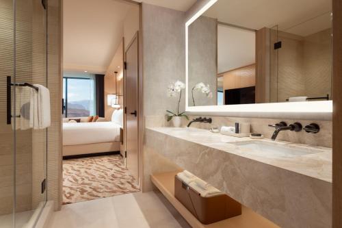 拉斯维加斯Durango Casino & Resort的一间带两个盥洗盆和镜子的浴室以及一张床