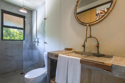 埃斯孔迪多港Raíz Hotel Boutique的一间带水槽、卫生间和镜子的浴室