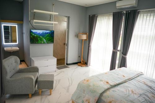 BedoyoVilla Languket I的一间卧室配有一张床、一台电视和一把椅子