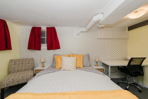 埃德蒙顿Quaint & Cozy Accommodation的一间卧室配有一张床、一张书桌和红色窗帘