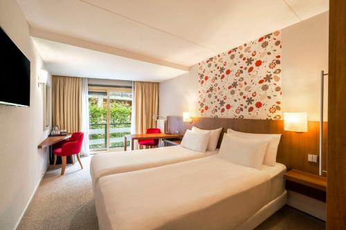 宁斯佩特Fletcher Hotel-Restaurant Sparrenhorst-Veluwe的酒店客房设有一张大床和一张书桌。