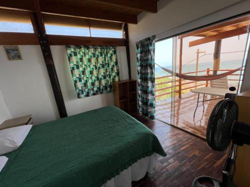 曼克拉Pocitas Casa Hotel - Playa & Piscina的一间带绿色床的卧室和一个阳台