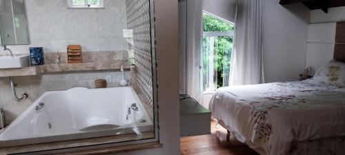 伊泰帕瓦Casa de Campo - Vista da montanha的一间位于床边的带浴缸的浴室