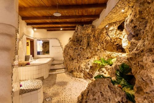 塔纳岛Rockwater Resort的一间带岩石墙和浴缸的浴室